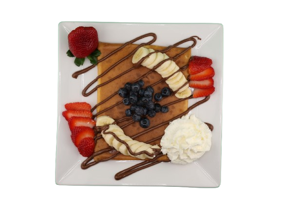 Crepe topped with banana, strawberries, blueberries, whipped cream, and chocolate drizzle